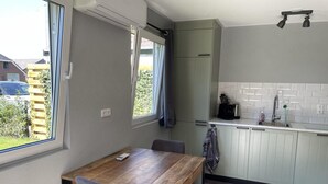 A compact kitchen with a dining table, a window, and a built-in oven. - Beautiful Accommodation in De Kiel (De Kiel)