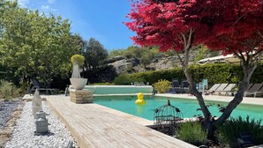 Un área de piscina con cubierta de madera, sillas de descanso y un flotador inflable amarillo.
