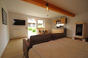 Un dormitorio con cama, televisión, kitchenette y vistas al exterior.