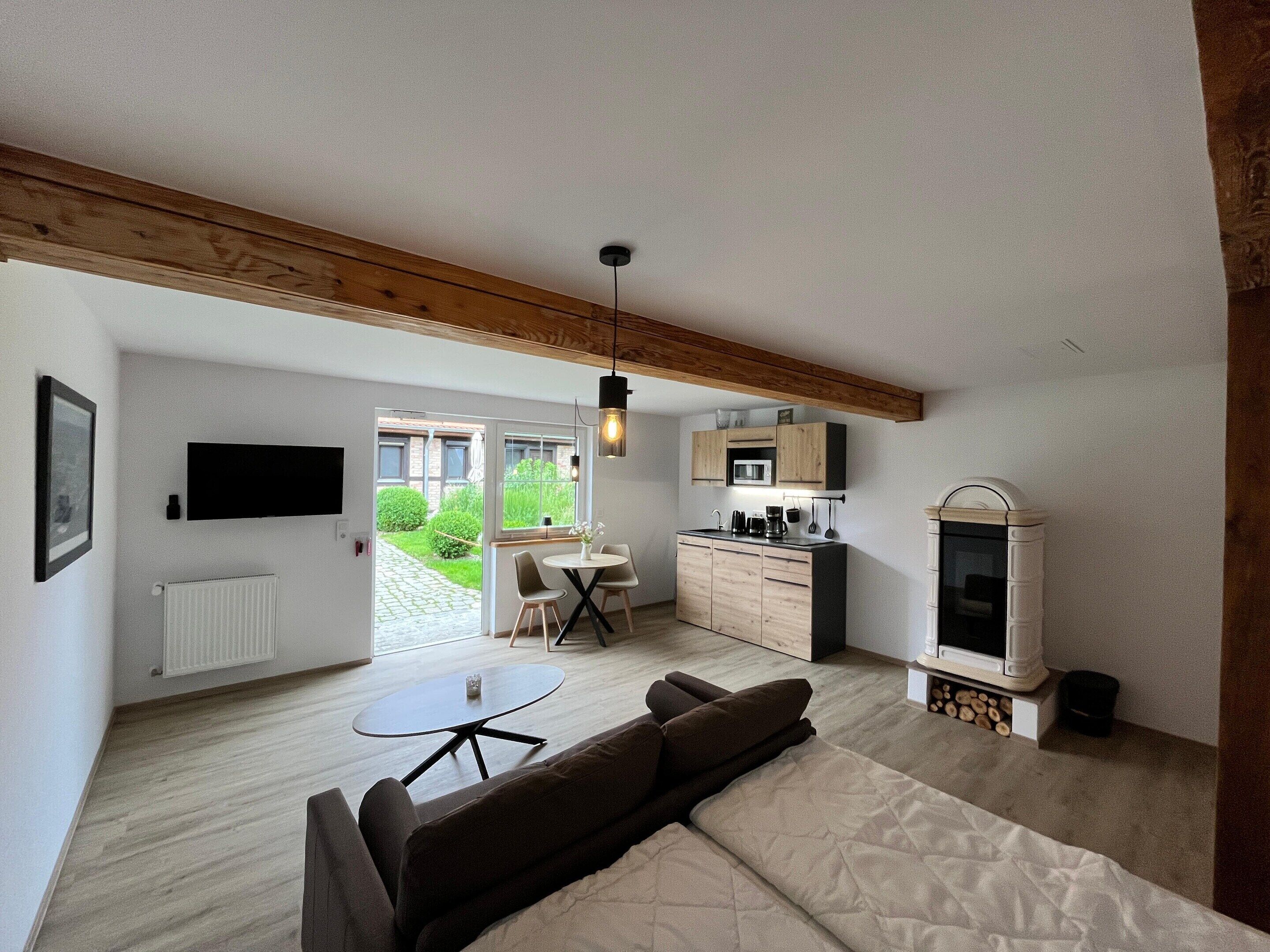 A modern living room with a sofa, a small table, and a kitchen area with a microwave and cabinets.
