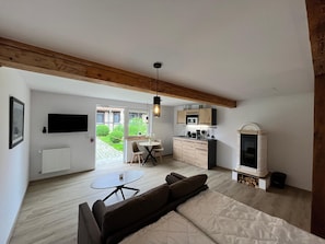 A modern living room with a sofa, a small table, and a kitchen area with a microwave and cabinets. - Neues Appartement Nr. 6 im Lepels Hof (Luetow)