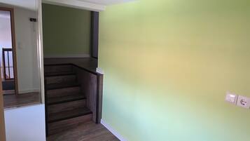 Ein Zimmer mit Holzboden, einer Treppe und einer grünen Wand.