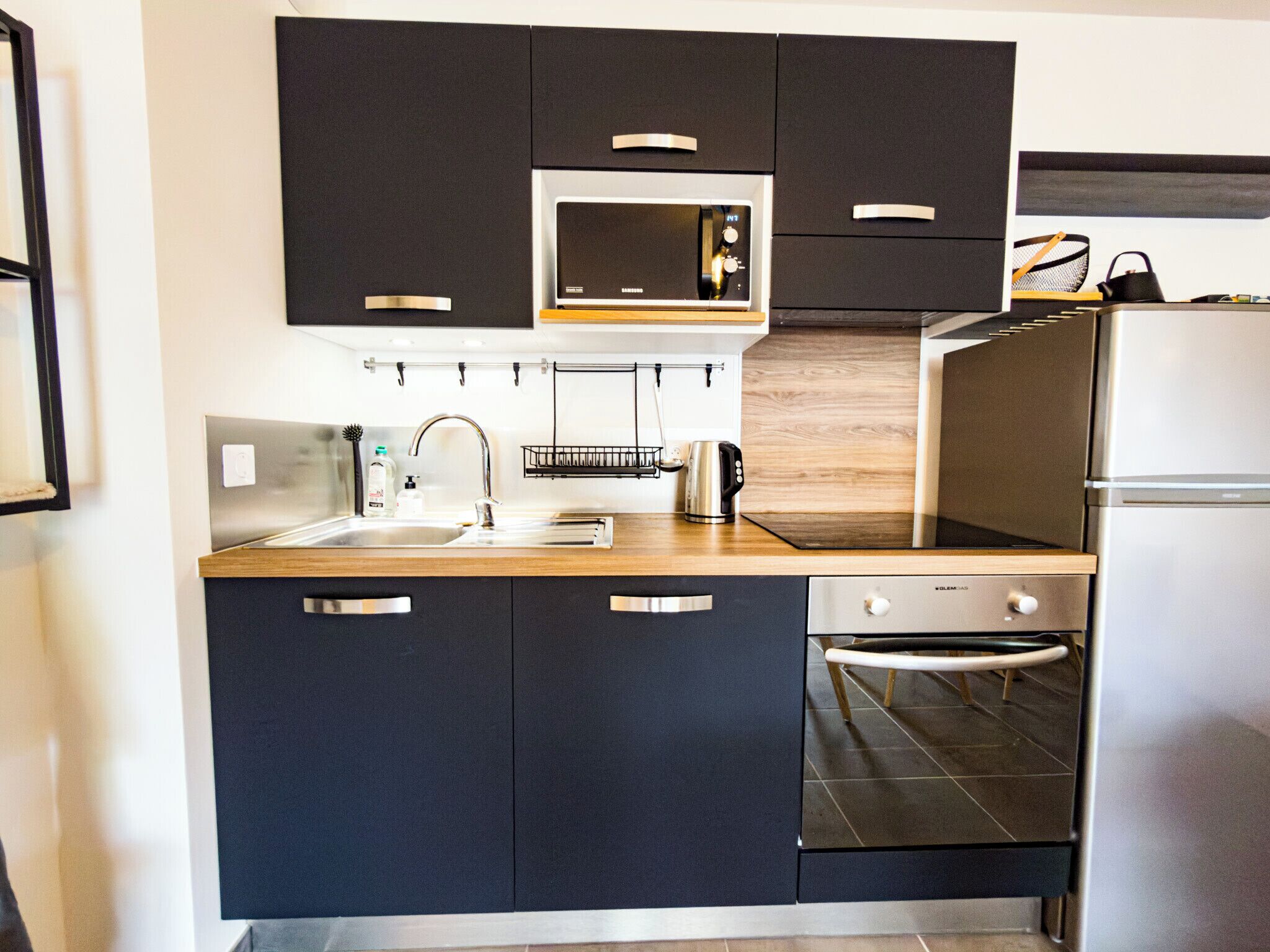 Een moderne keuken met een ingebouwde magnetron, oven en vaatwasser.
