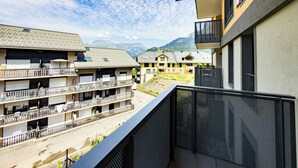 Un hotel moderno con varios balcones, vistas a las montañas y un cielo despejado.