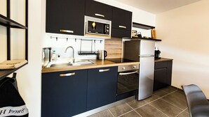 Una cocina moderna con gabinetes negros, electrodomésticos de acero inoxidable y encimera de madera.