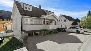 Een woonhuis met garage, oprit en geparkeerde auto.
