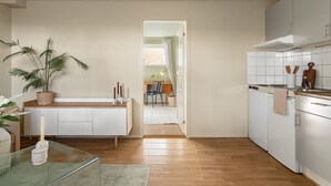 Een moderne keuken met witte kasten, een houten aanrechtblad en uitzicht op een eethoek.