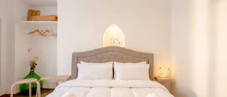 Una cama bien hecha con toallas enrolladas, un cabecero de madera y una mesita de noche con una lámpara.