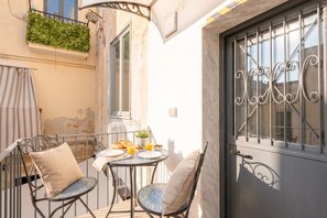 Ein kleiner Außenbereich zum Essen mit einem Tisch, zwei Stühlen und einem Fenster mit schmiedeeisernen Gitterstäben.