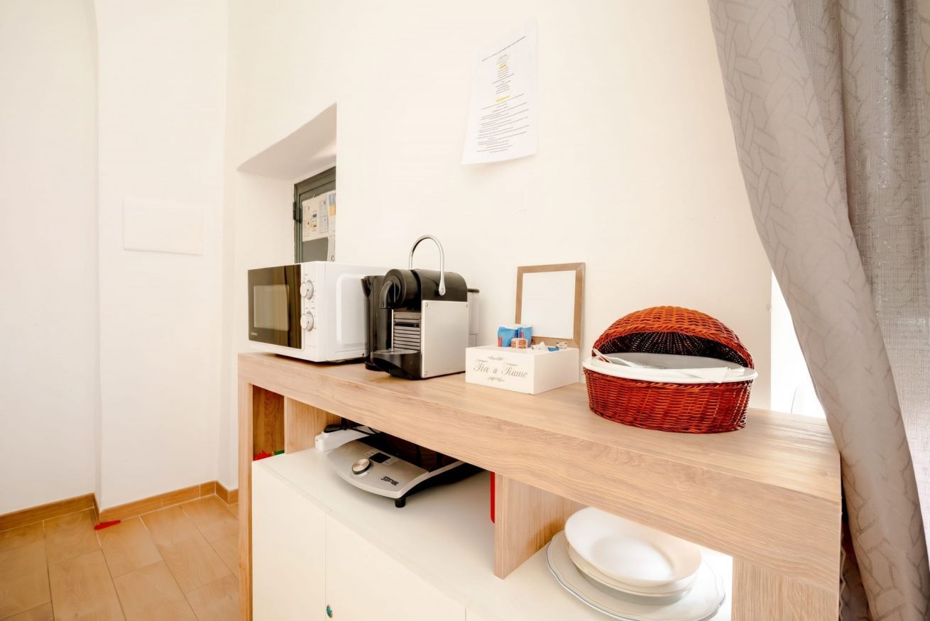 A kitchenette with a microwave, toaster, and basket on a wooden countertop.
