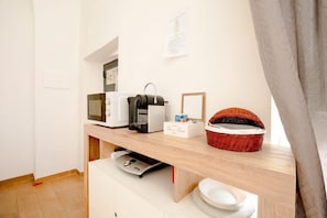 A kitchenette with a microwave, toaster, and basket on a wooden countertop. - Vecchia Bari Basilica San Nicola | Cozy Studio in Old Bari (Bari)