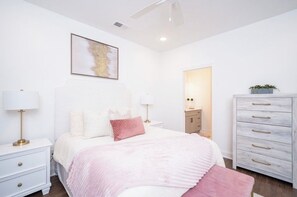 Ein Schlafzimmer mit einem Bett, Nachttischen, einer Kommode und einem Deckenventilator.