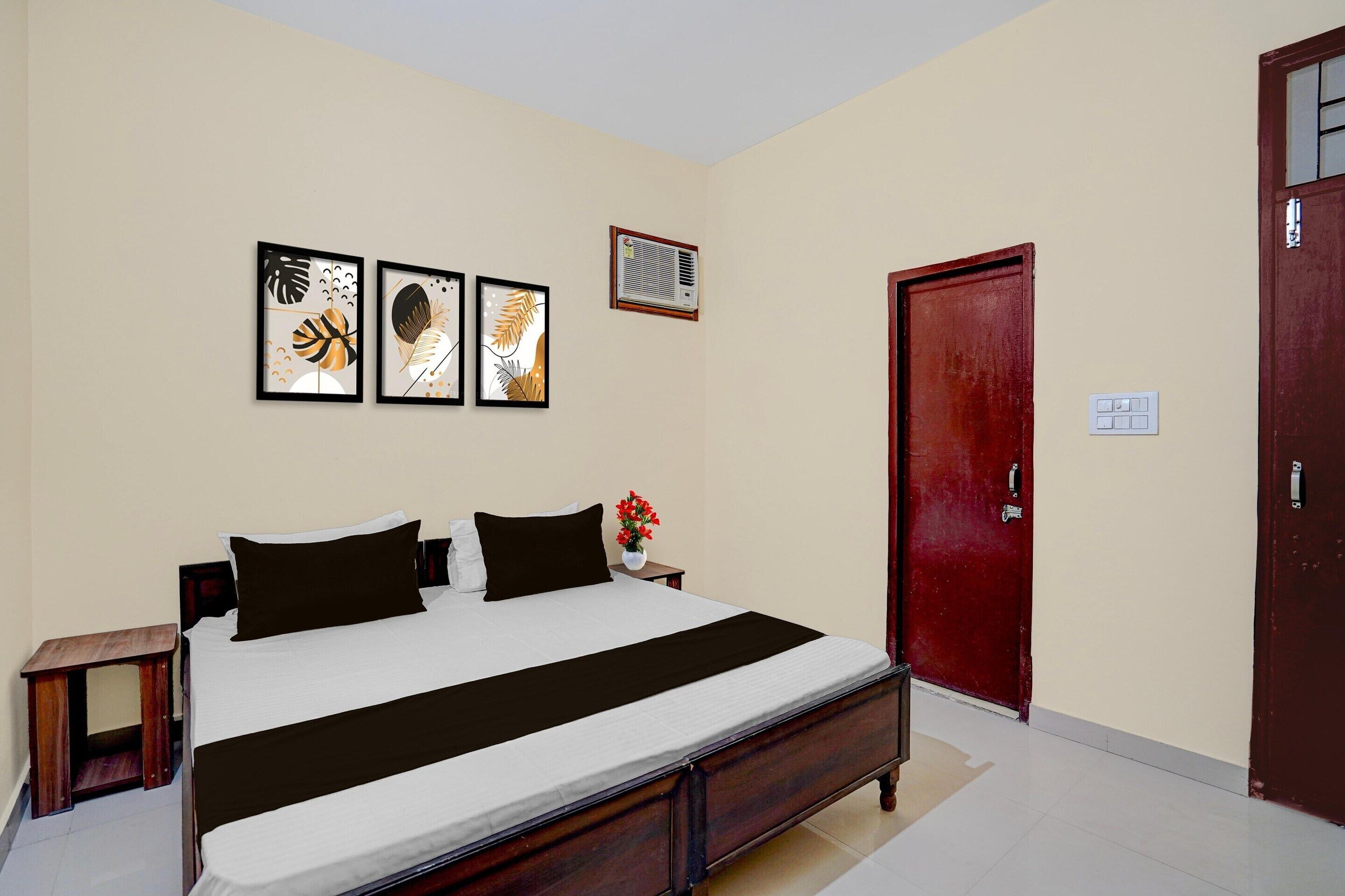 A bedroom with a bed, a nightstand, a wall-mounted air conditioner, and a door.
