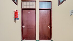 Two closed doors with numbers 203 and 202, a fire extinguisher on the wall, and a marble floor. - Deluxe Chandigarh Outer (Kharar)