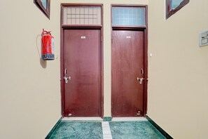 Zwei geschlossene Türen mit den Nummern 203 und 202, ein Feuerlöscher an der Wand und ein Marmorboden.