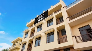 A multi-story building with balconies, a sign indicating 'Collection 2 floors serviced,' and a clear blue sky. - Deluxe Chandigarh Outer (Kharar)