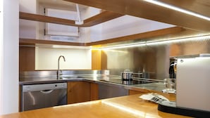 Una cuina moderna amb electrodomèstics d'acer inoxidable, taulells de fusta i forn integrat.