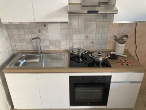 Eine Küche mit Spüle, Herd, Backofen und einer weißen Küchenrückwand.