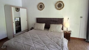 Un dormitorio con una cama grande, techo de madera, un armario y dos adornos de pared.