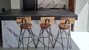 Una cocina con salpicadero de mármol, taburetes de madera y lámparas colgantes.