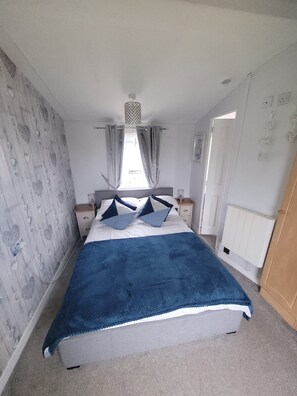 Ein Schlafzimmer mit einem Bett, Vorhängen, einem Heizkörper und einer Wand mit Muster.
