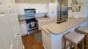 A kitchen with white cabinets, a stainless steel refrigerator, a microwave, and a stove. - Walk to the slopes!  2BR in The Reserve with iconic Grandfather Mountain views (Sugar Mountain)