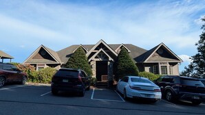 A building with a symmetrical facade, a central entrance, and a parking lot with several cars. - Walk to the slopes!  2BR in The Reserve with iconic Grandfather Mountain views (Sugar Mountain)