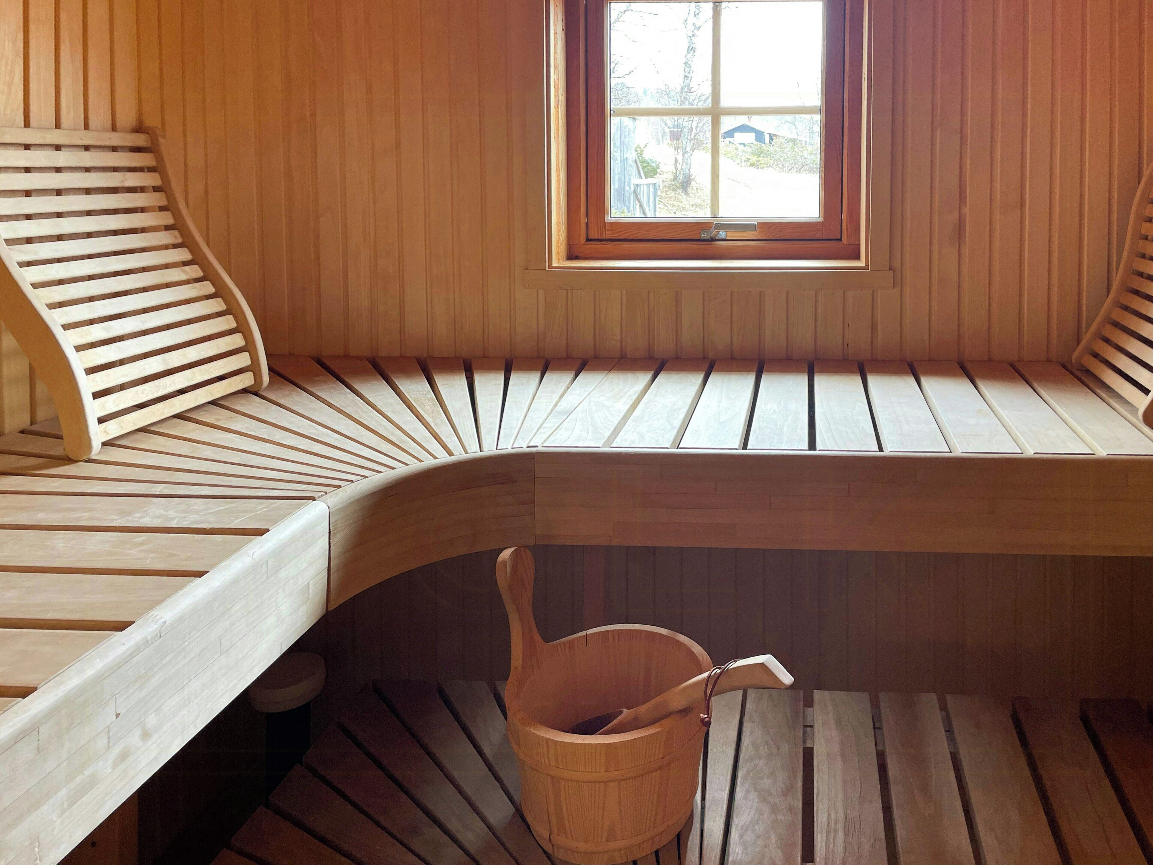 A wooden bench with a window, a wooden bucket, and a wooden table.