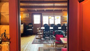 A wooden interior with a dining area, wooden ceiling beams, and a rug.