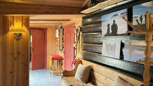 A wooden interior with a sofa, a red door, and a wall-mounted photo display.