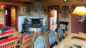A cozy cabin interior with a fireplace, wooden furniture, and a dining area.