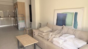 Een moderne woonkamer met een bank, een klein houten tafeltje en een keuken op de achtergrond.