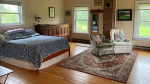Ein Schlafzimmer mit Bett, Sessel, Teppich und Kamin.