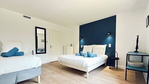 Habitación de hotel con dos camas, un espejo, un mueble bajo y una mesita de noche.