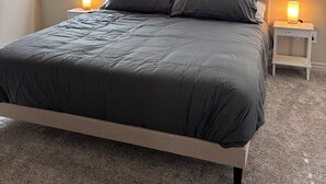 Una camera da letto con un letto, due comodini con lampade, una ventola a soffitto e un quadro astratto appeso alla parete.