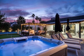 A hot tub with lounge chairs, a covered patio area with string lights, and a pool. - Solterra - Heated Pool, Hot Tub, Sauna, Pickleball (Scottsdale)