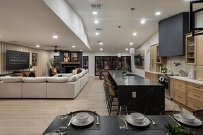 A modern kitchen with a central island, dining area with table set, and a living area with a sofa. - Solterra - Heated Pool, Hot Tub, Sauna, Pickleball (Scottsdale)