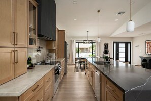 A modern kitchen with wooden cabinets, a black countertop, and a large island. - Solterra - Heated Pool, Hot Tub, Sauna, Pickleball (Scottsdale)