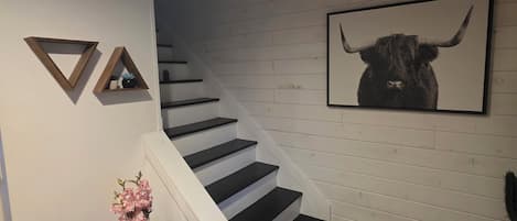 A staircase with black steps, white walls, and a framed bull picture.
