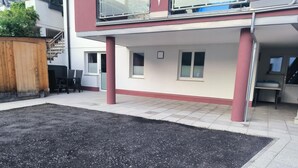 A residential building with a covered patio area, a wooden fence, and a staircase leading to an upper level. - Apartment in Strengen With Mountain Views (Strengen)