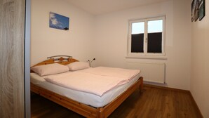 A bedroom with a wooden bed, a window, a radiator, and a wall-mounted picture. - Apartment in Strengen With Mountain Views (Strengen)