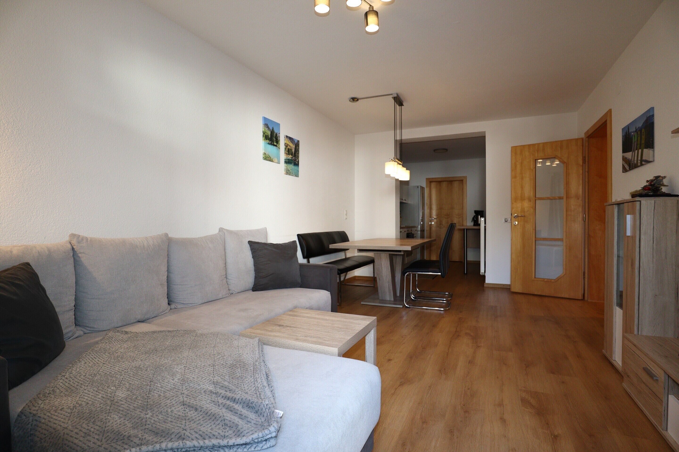 Ein modernes Wohnzimmer mit Sofa, Couchtisch und Essbereich.