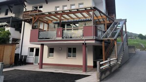 A two-story building with a covered outdoor area, a staircase, and a view of the surrounding landscape. - Apartment in Strengen With Mountain Views (Strengen)