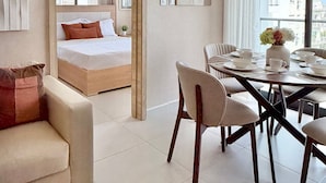 A modern hotel room with a bed, a dining table with chairs, a sofa, and an air conditioning unit. - City Center| Pool and Gym 1BR by YellowKey (Santo Domingo)