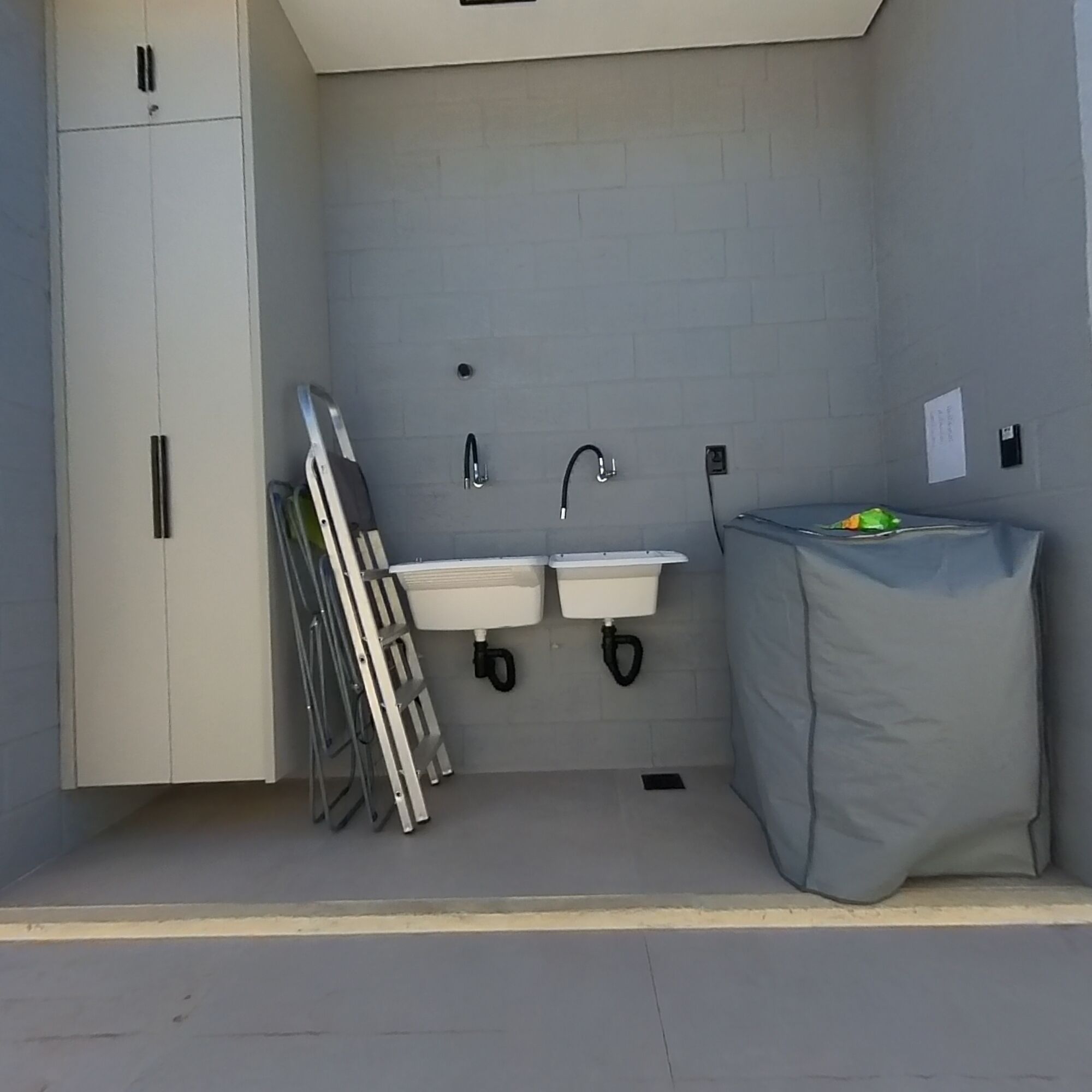 A compact bathroom with two sinks, a toilet, and a covered trash bin.