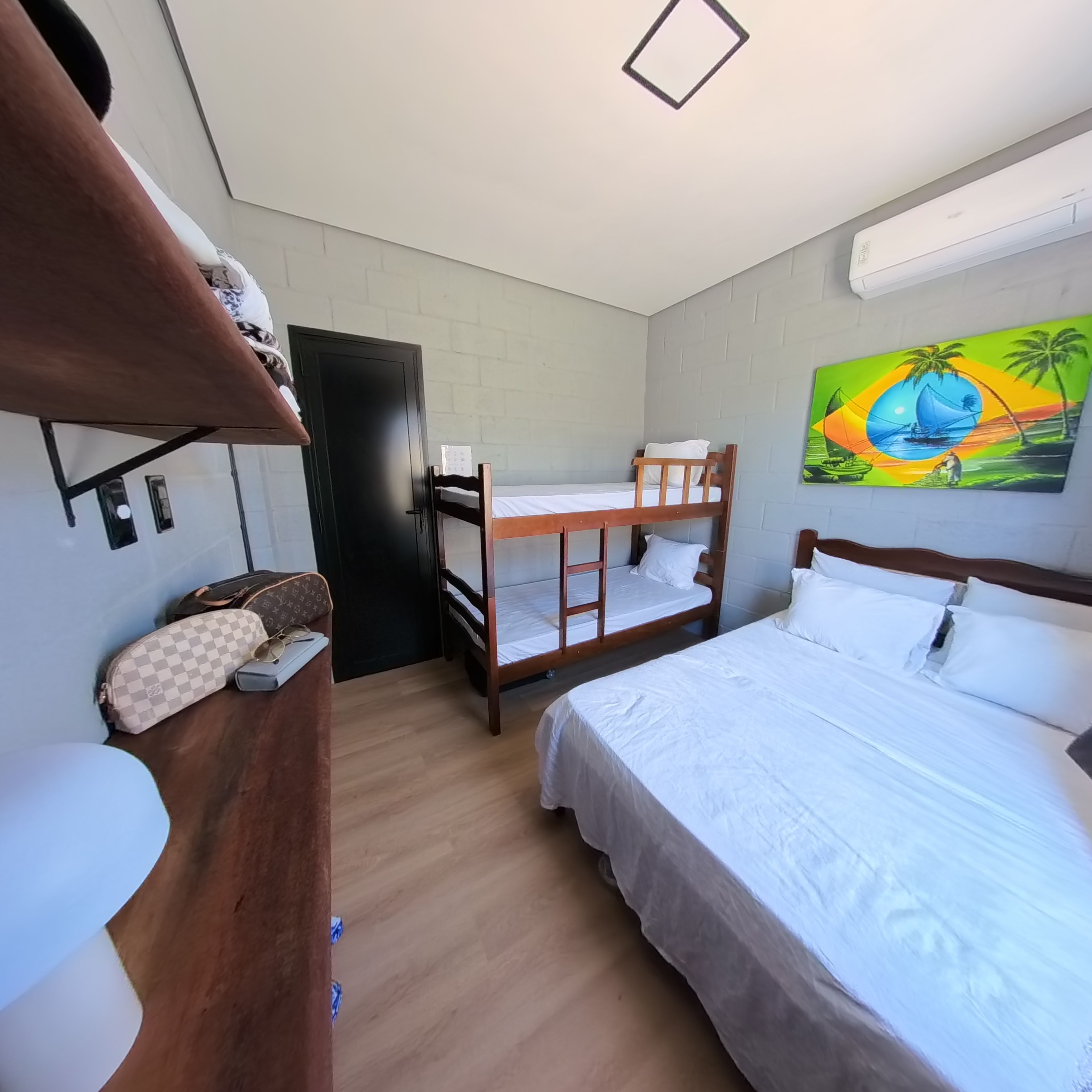 Ein Zimmer mit einem Etagenbett, einem Schreibtisch mit Stuhl, einem Kleiderschrank und einem Bild an der Wand.