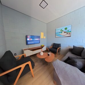 En moderne stue med et fladskærms TV, et billede og et spiseområde med et bord og stole.