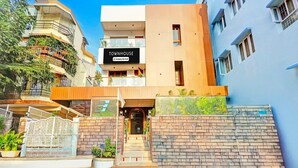 Une maison de ville moderne avec une enseigne indiquant « TOWNHOUSE, services d’entreprise », une entrée sécurisée par un portail et un mur de briques agrémenté de verdure.