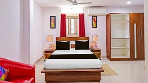 Une chambre à coucher avec un lit, une chaise rouge, une armoire et un ventilateur de plafond.
