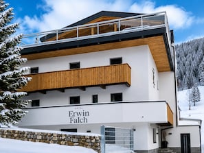 A modern hotel with a wooden balcony, a stone wall, and a sign reading 'Erwin Falch.' - Apartment in St. Anton With Sauna (Sankt Anton am Arlberg)